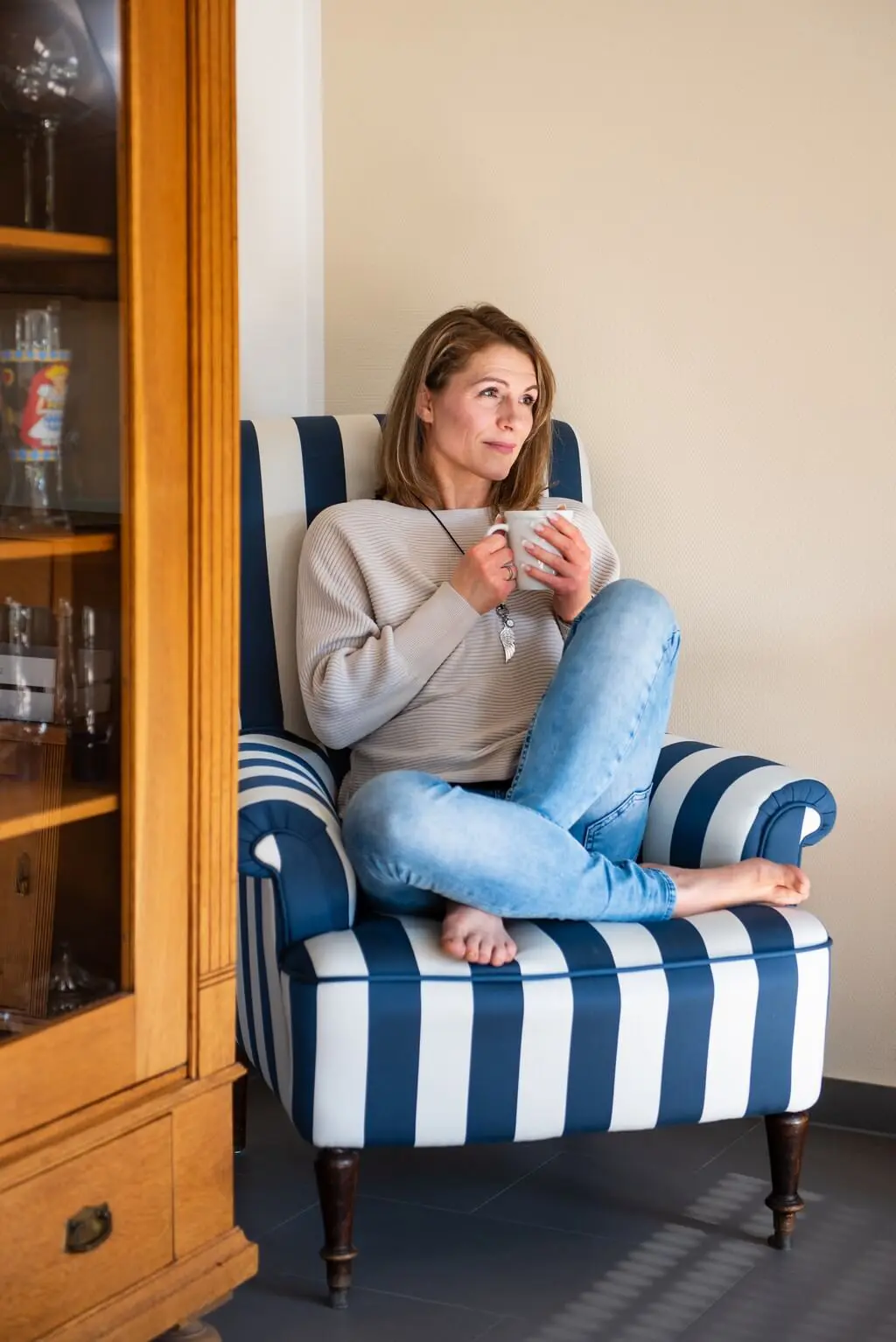 Frau auf gemütlichem Sessel trinkt Kaffee und genießt